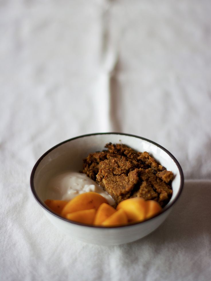 a bowl filled with fruit and yogurt on top of a white table cloth