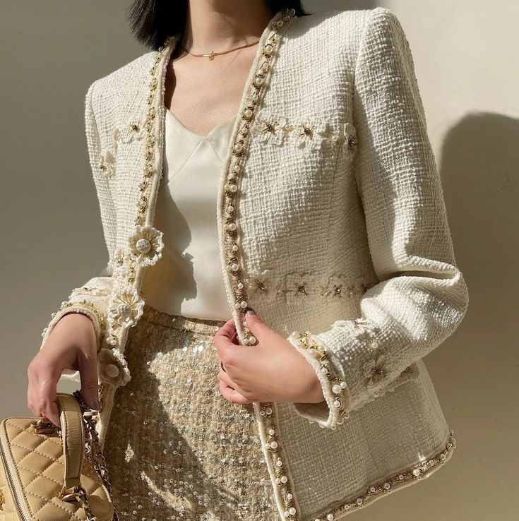 Elevate your style with this exquisite handmade tweed bouclé jacket, a true masterpiece in fashion. Crafted with meticulous attention to detail, this 3D ivory floral jacket is adorned with delicate pearls and shimmering metallic accents, adding a touch of luxury to your wardrobe. The intricate floral design creates a stunning visual effect, giving the jacket a dimensional and elegant look. Each pearl and metallic detail is carefully placed to enhance the beauty of the piece, making it a standout Pearl Jacket Outfit, Luxury Elegant Tweed Jacket, Elegant Winter Tweed Jacket With Button Closure, Elegant Cream Tweed Jacket, Luxury Chic Beige Tweed Jacket, Elegant Tweed Outerwear With Button Closure, Tweed Boucle Jacket, Boucle Jacket, Beautiful Suit