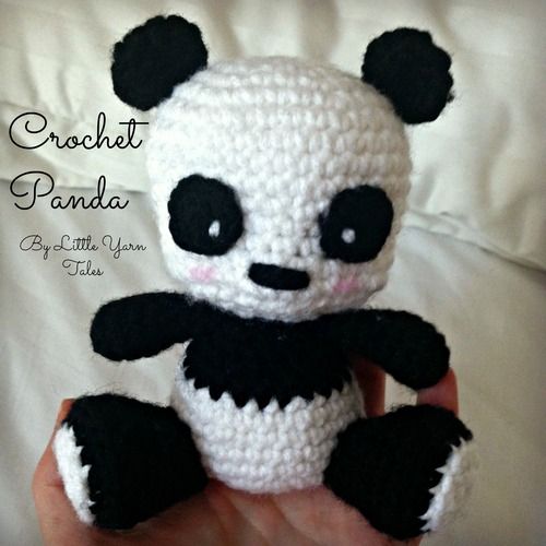 a crocheted panda bear sitting on top of a bed