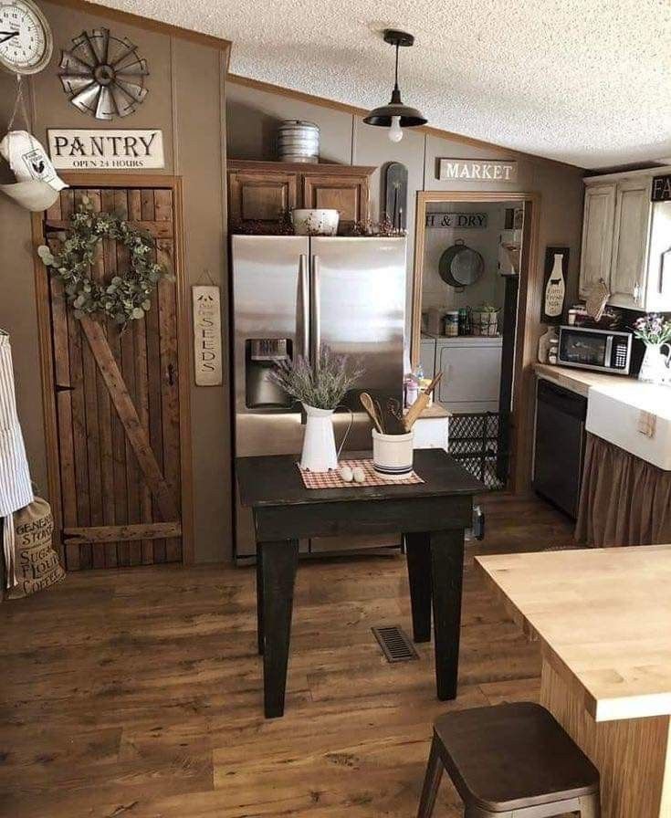 a kitchen with wooden floors and white walls, has a small table in front of the refrigerator