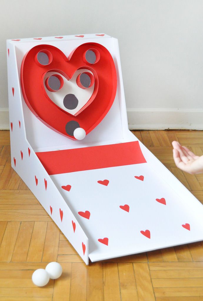 an open cardboard box with a paper heart in it and some balls on the floor