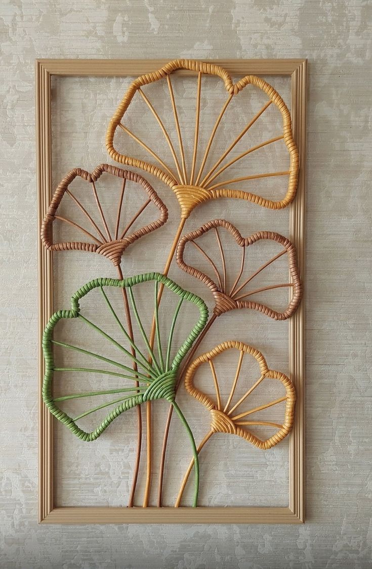 an art piece made out of wicker with green stems in the center and leaves on each side