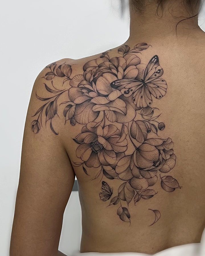 a woman's back with flowers and butterflies on it