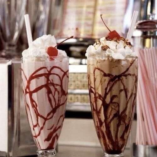 two glasses filled with ice cream and chocolate milkshakes next to each other on a counter