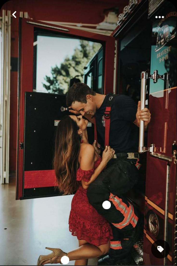 a man and woman kissing in front of a firetruck with the door open