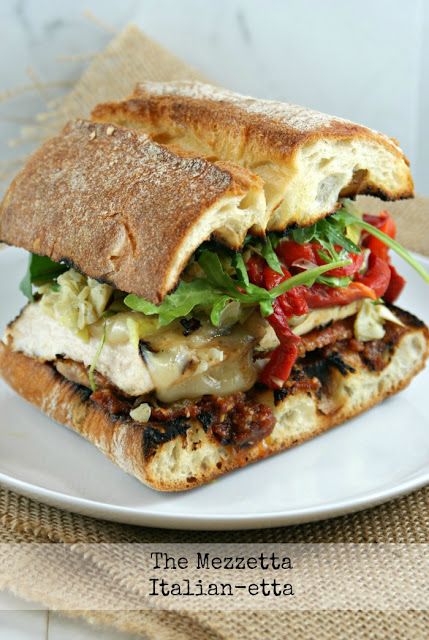 a sandwich with meat, lettuce and tomato on it sitting on a plate