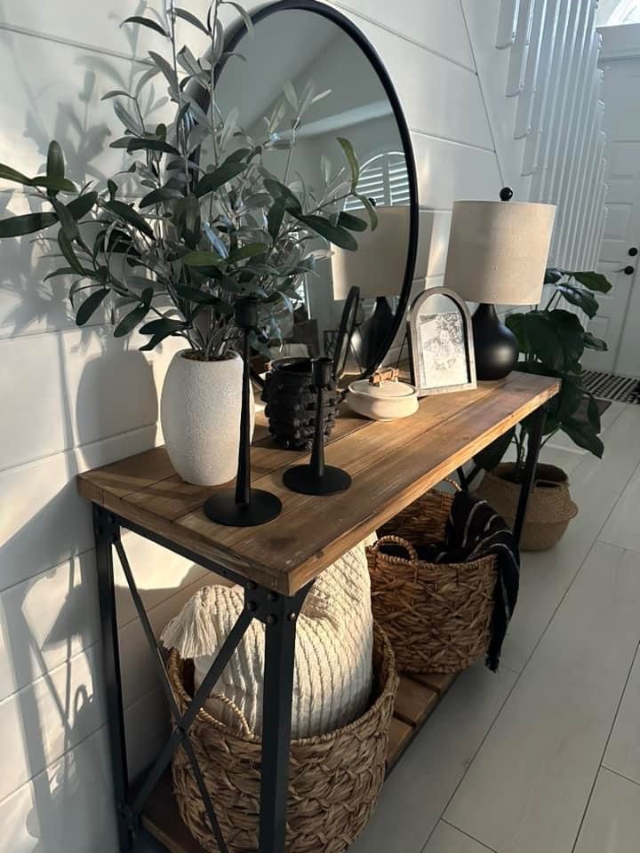 a wooden table topped with a mirror and two baskets filled with plants on top of it