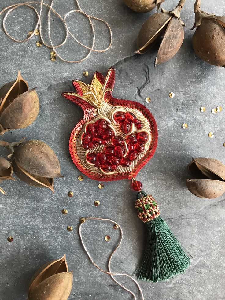 the pomegranate has been made with gold and red beads, which are hanging from