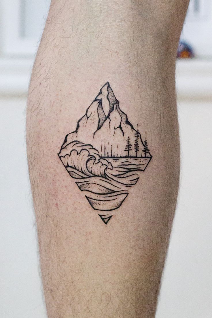 a man's leg with a mountain and lake tattoo on the left side of his calf