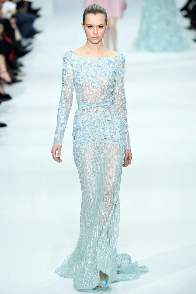 a model walks down the runway in an embellished gown with long sleeves and open back