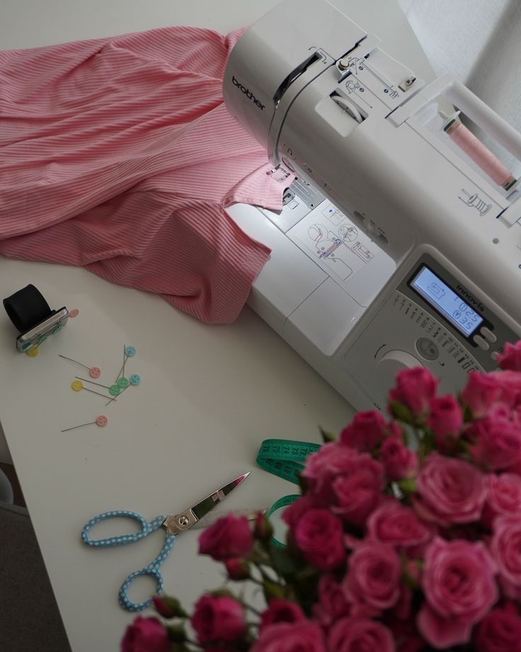 the sewing machine is next to some pink roses