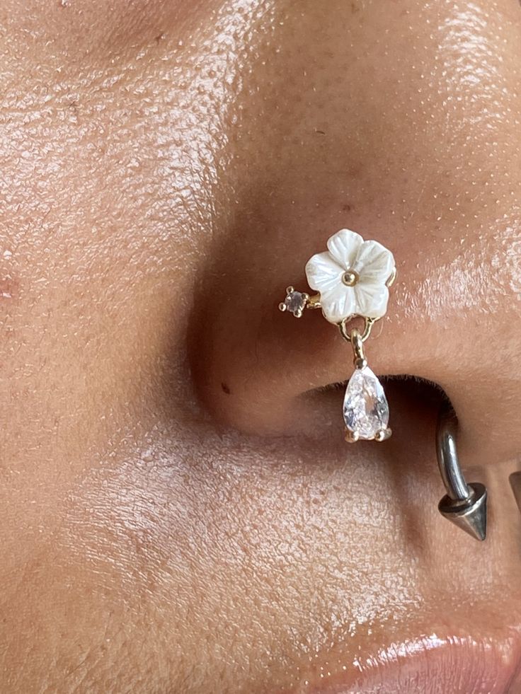 a close up of a woman's nose with an ear piercing and flower on it