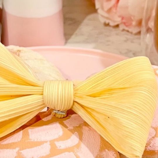 a yellow bow tie sitting on top of a pink towel next to a cup and saucer