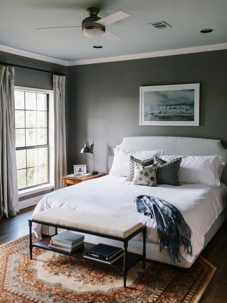 a bed with white sheets and pillows on top of it next to a large window