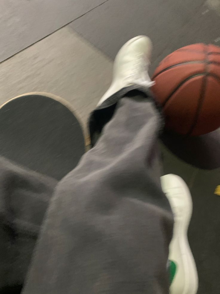 a person's feet with white sneakers and a basketball