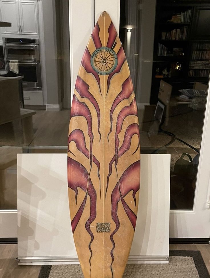 a wooden surfboard sitting on top of a rug in front of a door way