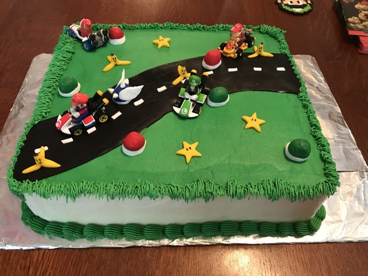 a birthday cake is decorated with green frosting and people riding motorcycles on the road