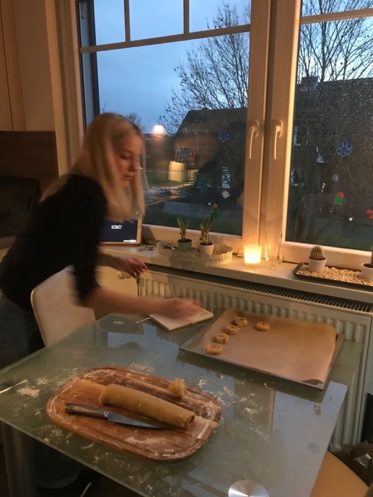 a woman standing in front of a window preparing food