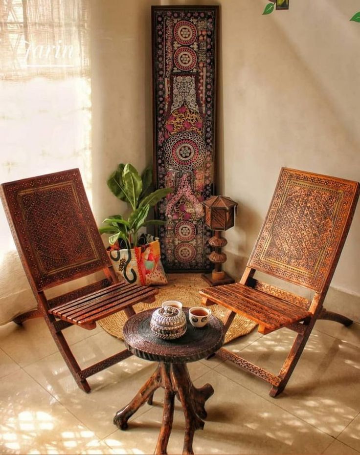 two wooden chairs sitting next to each other in front of a painting on the wall