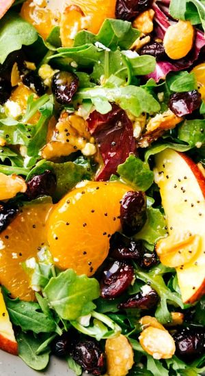 a salad with oranges, spinach and cranberries is shown in a bowl