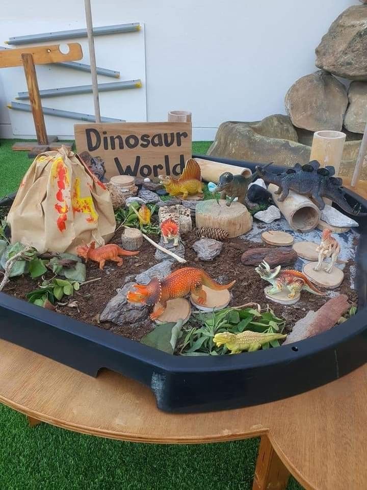 there is a dinosaur world in the middle of a table with rocks and plants on it