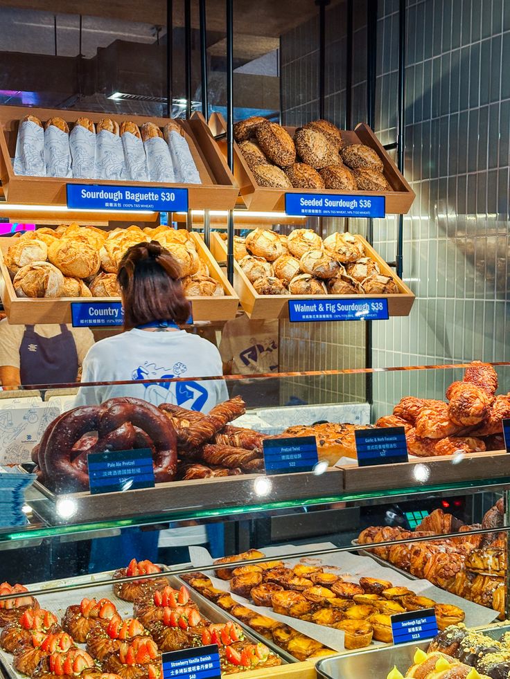 a woman standing in front of a bakery filled with pastries