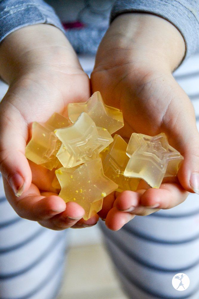 the child is holding several pieces of yellow glass in their hands, which are shaped like stars