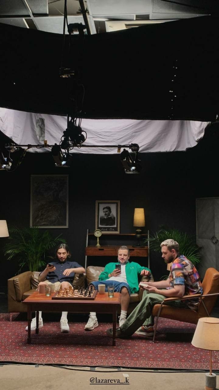 three people sitting on couches in front of a table with two dogs and one cat