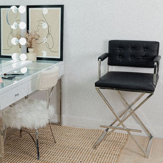 a white desk with a black chair in front of it and two pictures on the wall