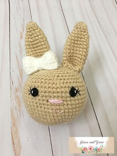 a crocheted stuffed animal with a white bow on its head sitting on a wooden surface