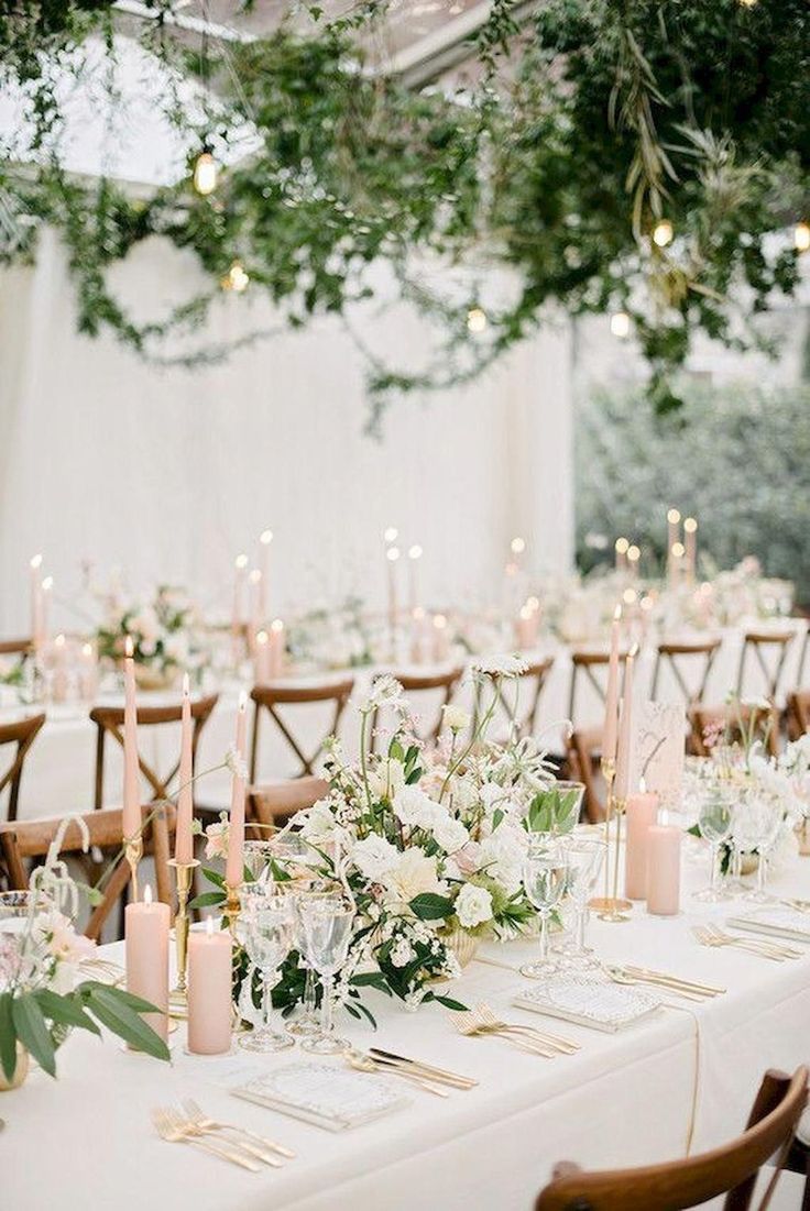 the tables are set with white flowers and greenery for an elegant wedding reception in a tented area