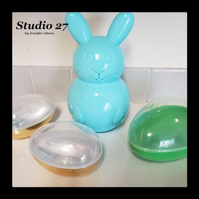 a blue bunny sitting next to two bowls on top of a white tile countertop