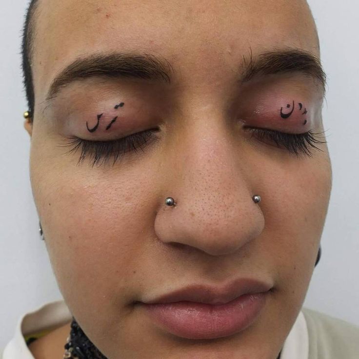 a close up of a person with nose piercings on their forehead and eyes closed