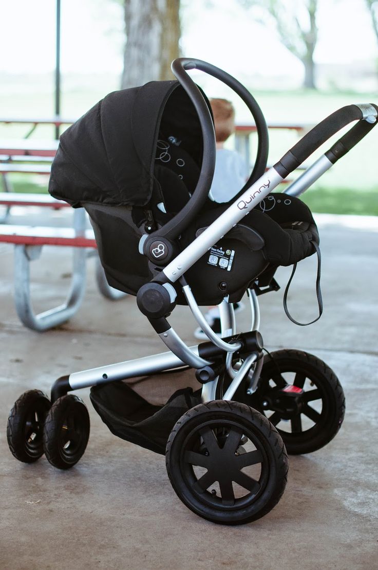 a baby stroller sitting on top of a cement floor next to a park bench