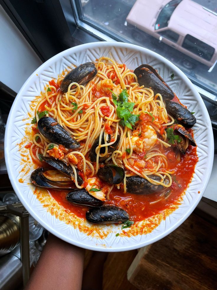 a white plate topped with spaghetti and mussels