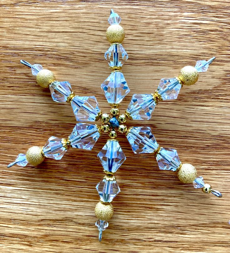 a snowflake made out of glass beads on a wooden surface with gold accents