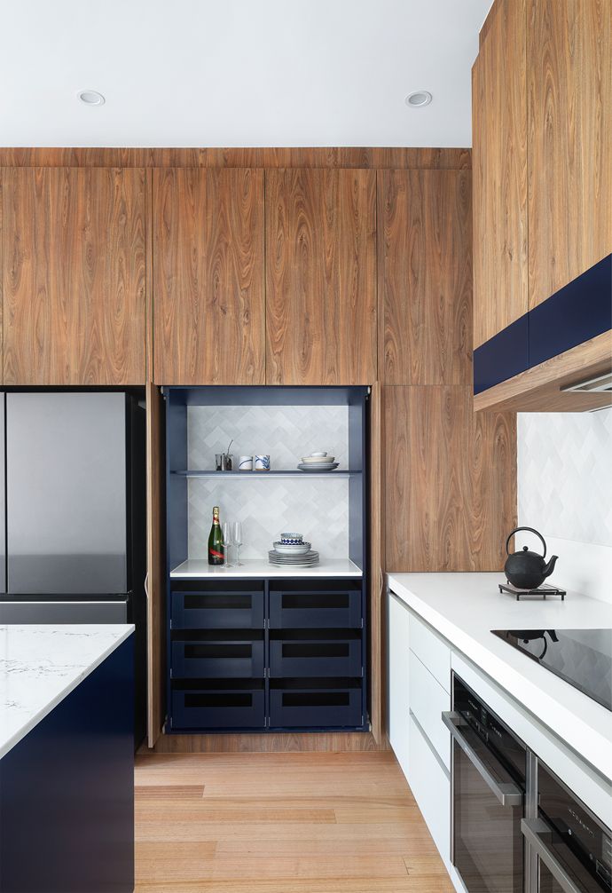 a modern kitchen with wood paneling and white counter tops, along with black appliances