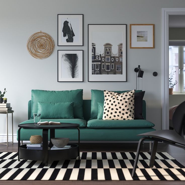 a living room with green couches and pictures on the wall above it's coffee table