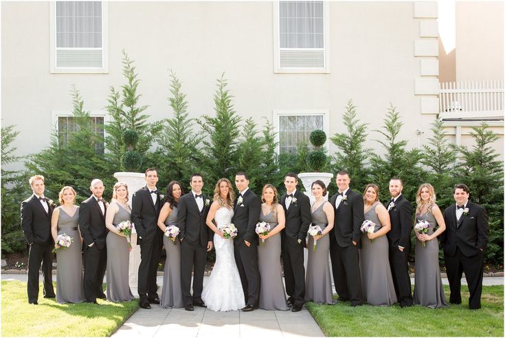 a large group of people in formal wear posing for a photo on their wedding day