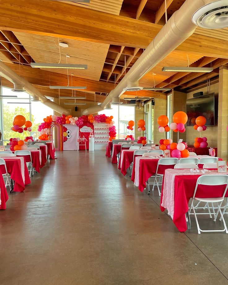 tables with red and orange tablecloths are set up in an open space for a party