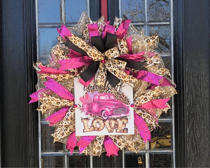 a pink and black wreath with the word love on it in front of a door