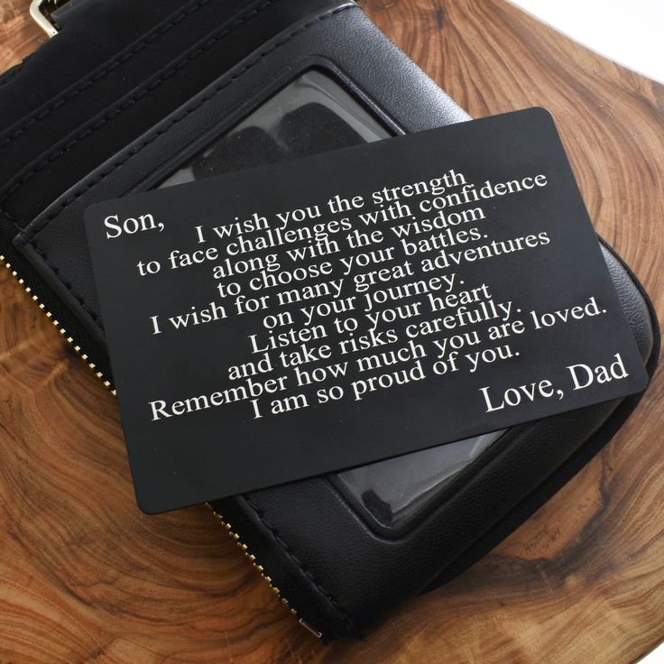 a wallet with a poem on it sitting on top of a wooden table next to a cell phone