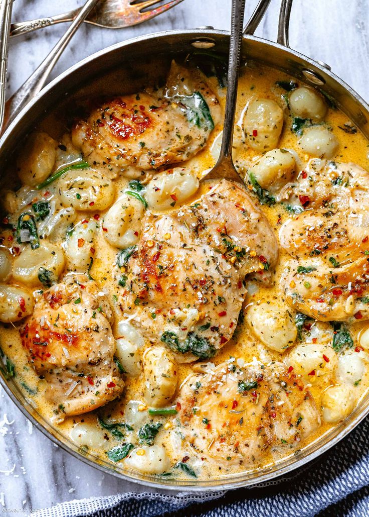 a skillet filled with chicken, potatoes and spinach