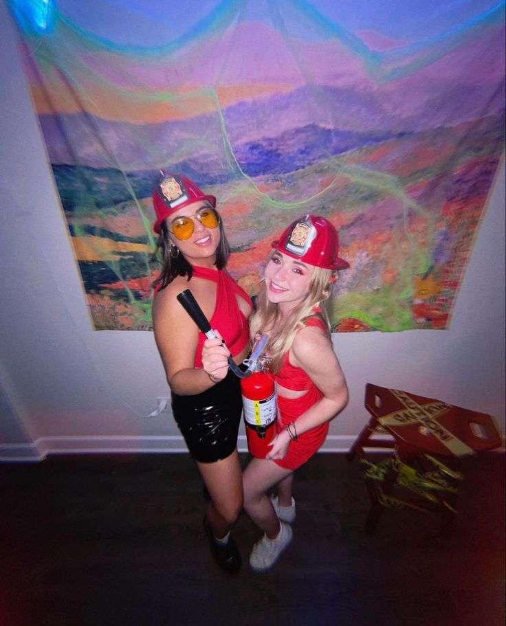 two women dressed up in costumes posing for the camera with one holding a fire extinguisher