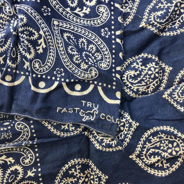 a blue and white paisley print fabric with gold foiling on it's edges