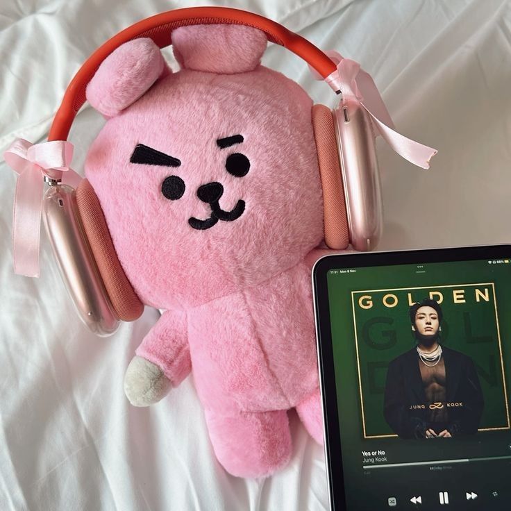 a pink teddy bear with headphones next to an mp3 player