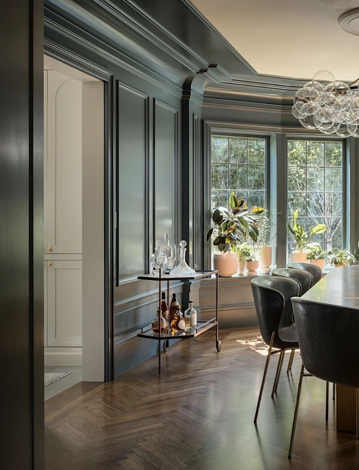 the dining room table is surrounded by black chairs and glass chandelier, along with potted plants