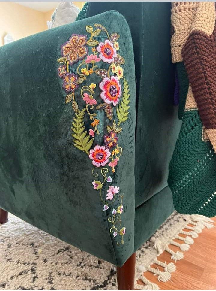 a green velvet couch with embroidered flowers on it