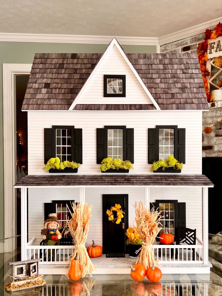 a doll house with pumpkins and corn on the windowsill