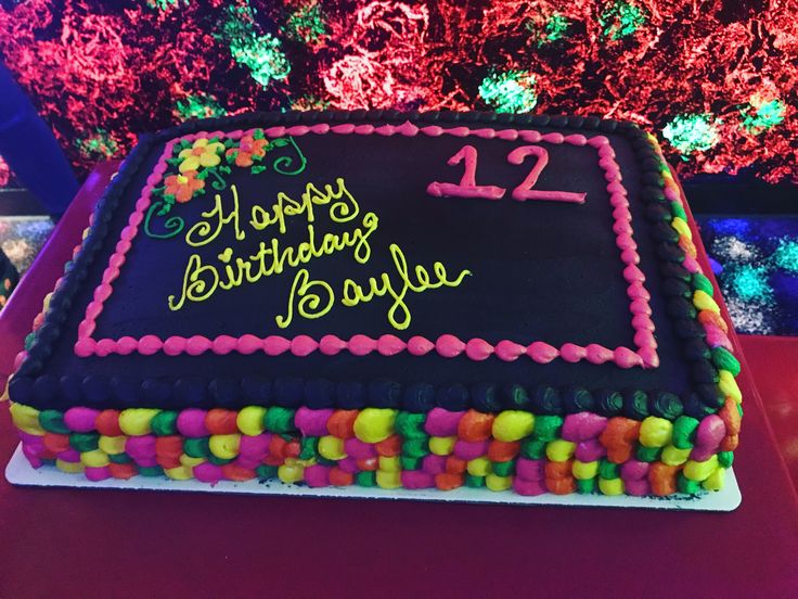 a birthday cake with the number twelve on it is displayed in front of colorful lights